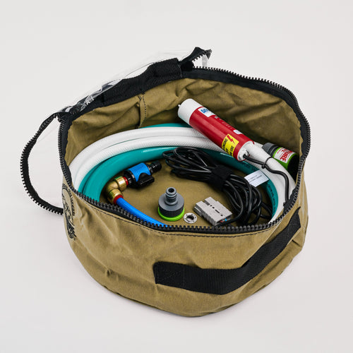 A khaki round zippered bag containing a coiled hose, cables, a red spray can, adapters, and connectors, all neatly arranged inside against a white background.