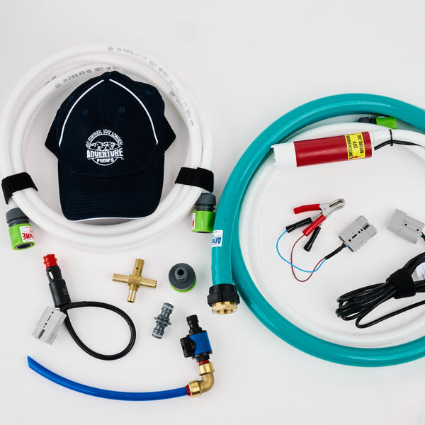 Hoses, connectors, cables, a brass fitting, and a navy Adventure Pumps hat are arranged on a white surface. The items appear to be parts for a water pump system.