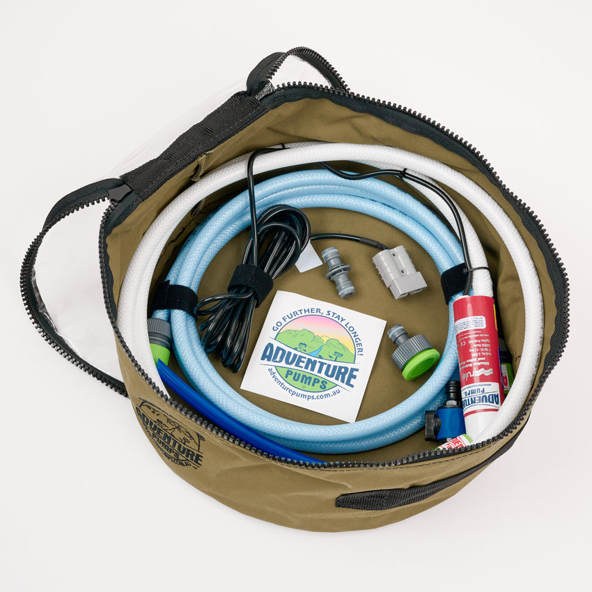The Adventure Pumps Universal 12V Water Transfer Pump Kit Bundle (WITH Canvas Bag) includes coiled blue and white hoses, connectors, a universal pump, Anderson plug, small red canister, black cable, and sticker—ideal for water transfer needs.