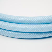 Close-up of the 1 x 5 meter extension hose inc fittings, light blue with a white crisscross pattern, coiled on a white background—ideal for Adventure Pumps or connecting to water tanks.