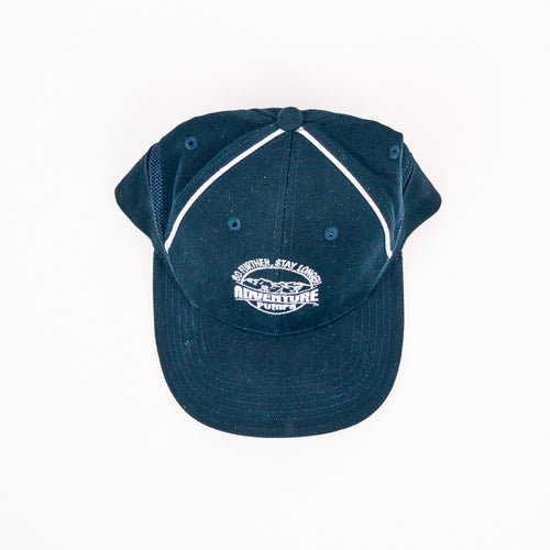 The Adventure Pumps Hat is a navy blue cap with white piping and Adventure Fun embroidered alongside a mountain graphic on the front. This stylish hat is shown against a white background.
