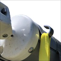 Close-up of an Awning Tie Down Clips – Pair: stainless steel hooks with bright yellow straps, screwed onto a cylindrical metal object—perfect for securing roll out awnings—shown on a white background.