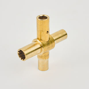 The Brass anti-vandal tap tool is a cross-shaped mechanical part with four grooved cylindrical arms, photographed on a plain white background.